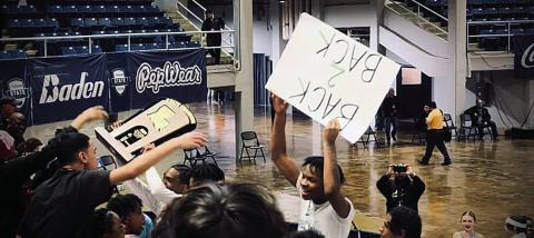 PHS basketball players hoist the state championship trophy and a fan poster reading, “BACK 2 BACK,” signifying the Wave’s second consecutive state title (Photo Courtesy Eli Peltier)