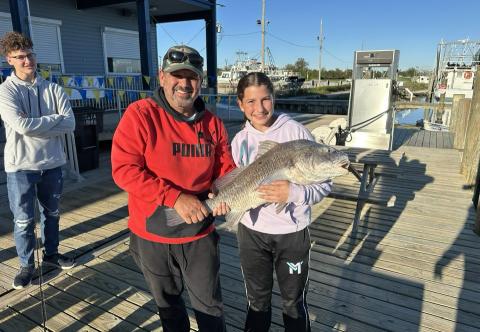 Russell Mayeur and his daughter Leah pose with the big redfish she reeled in for the second time. At left, her brother Noah admires the catch. (Courtesy Photo)