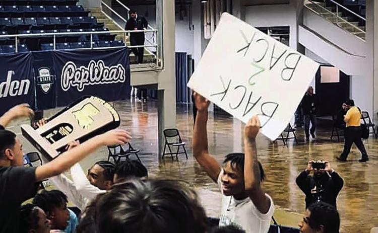 PHS basketball players hoist the state championship trophy and a fan poster reading, “BACK 2 BACK,” signifying the Wave’s second consecutive state title (Photo Courtesy Eli Peltier)