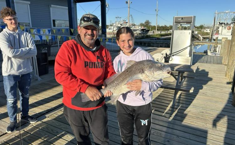 Russell Mayeur and his daughter Leah pose with the big redfish she reeled in for the second time. At left, her brother Noah admires the catch. (Courtesy Photo)